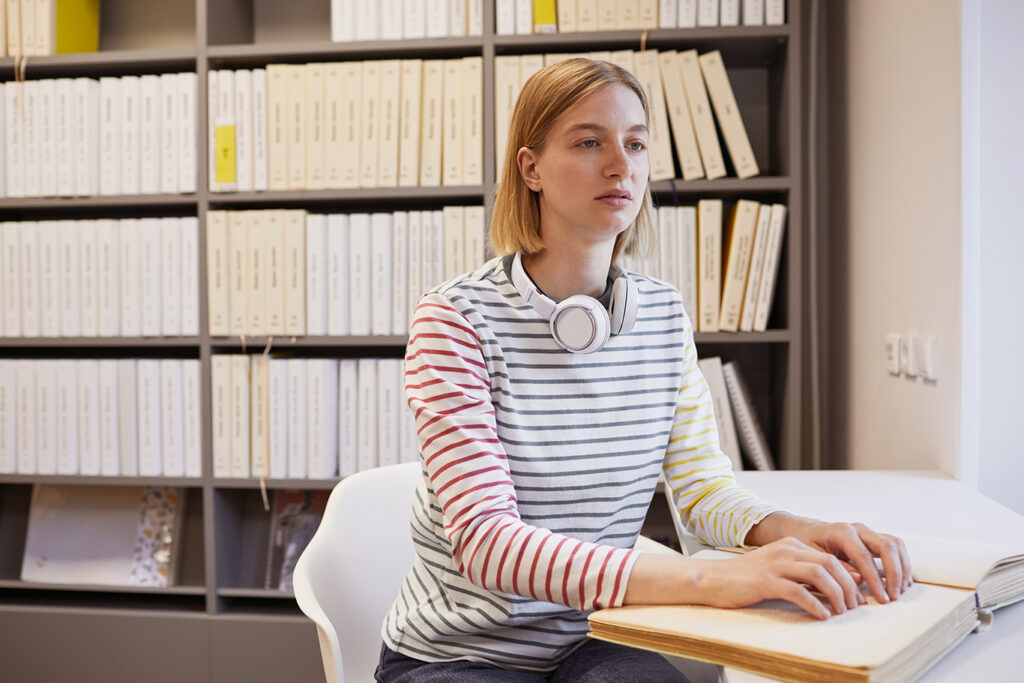 Girl reading a Braille book with headphones around her neck