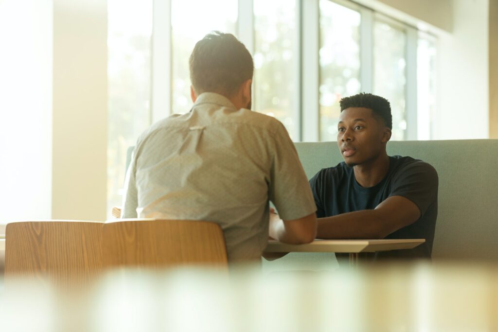 Two people sitting at a table talking. 