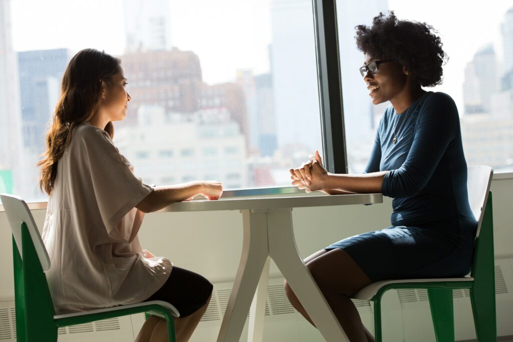 Two young people sitting at a table talking. 