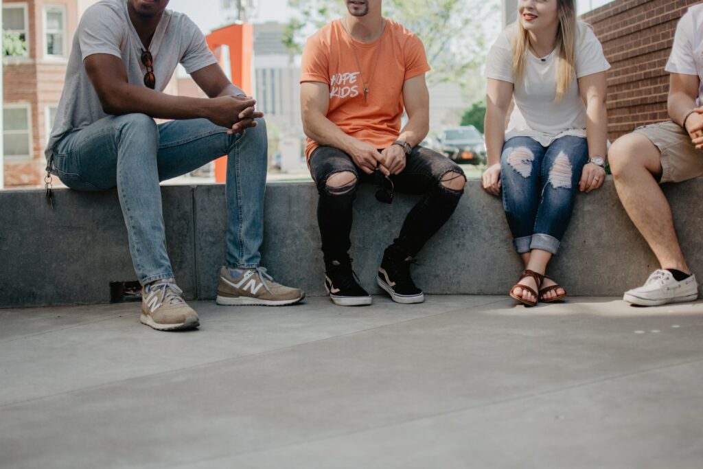 Four students sit outside talking.