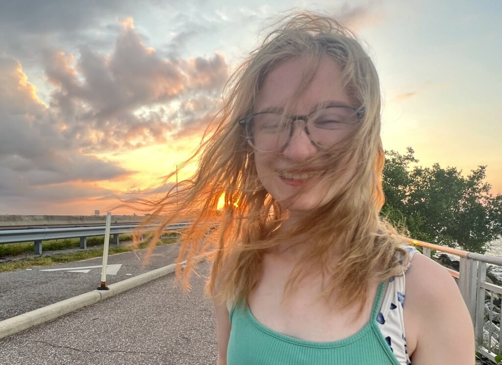 Female wearing eyeglasses while standing on a bridge overlooking water