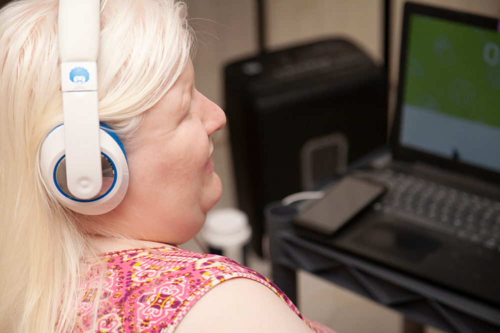 Person with albinism uses laptop with headphones